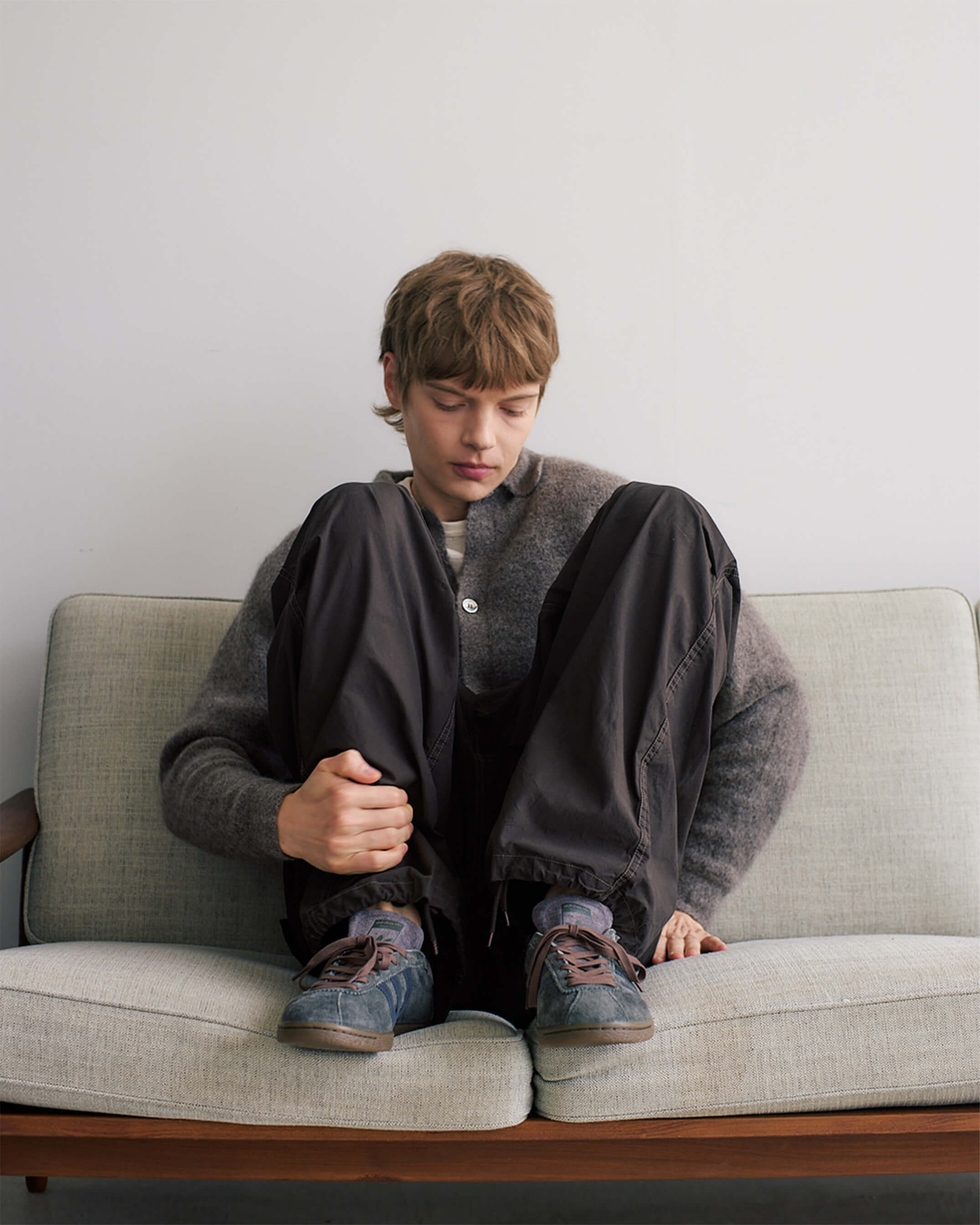 ソファーの上で膝を抱えている男性